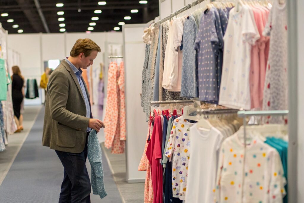 A person inspecting kids' clothing at a trade show booth, exploring various designs