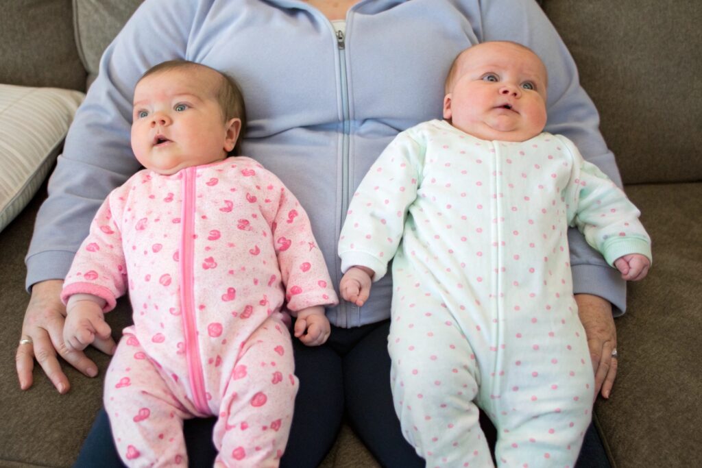 Parent comparing two babies in soft pajamas
