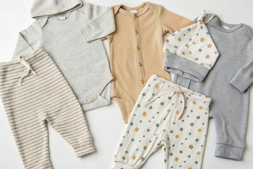 Premium organic baby clothes set, including onesies, pants, and a hat in soft colors