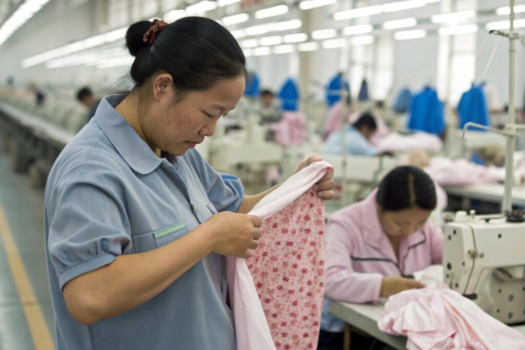 Worker inspecting pink fabric in factory