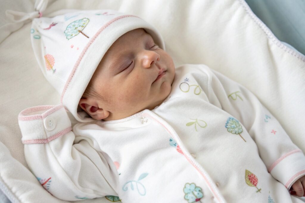Newborn baby in soft cotton onesie with pastel prints