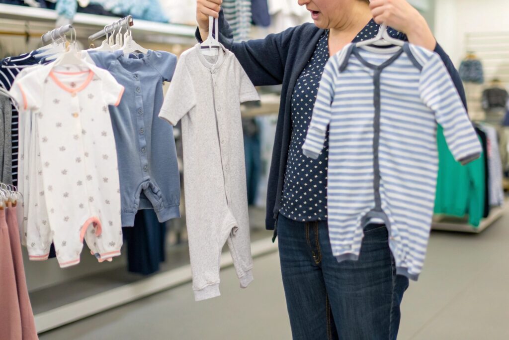 A parent inspecting children's clothing items in a store