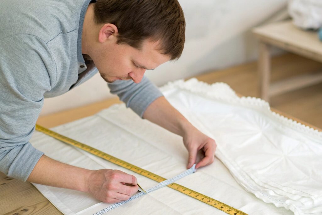 Garment designer measuring white cotton fabric with precision tools