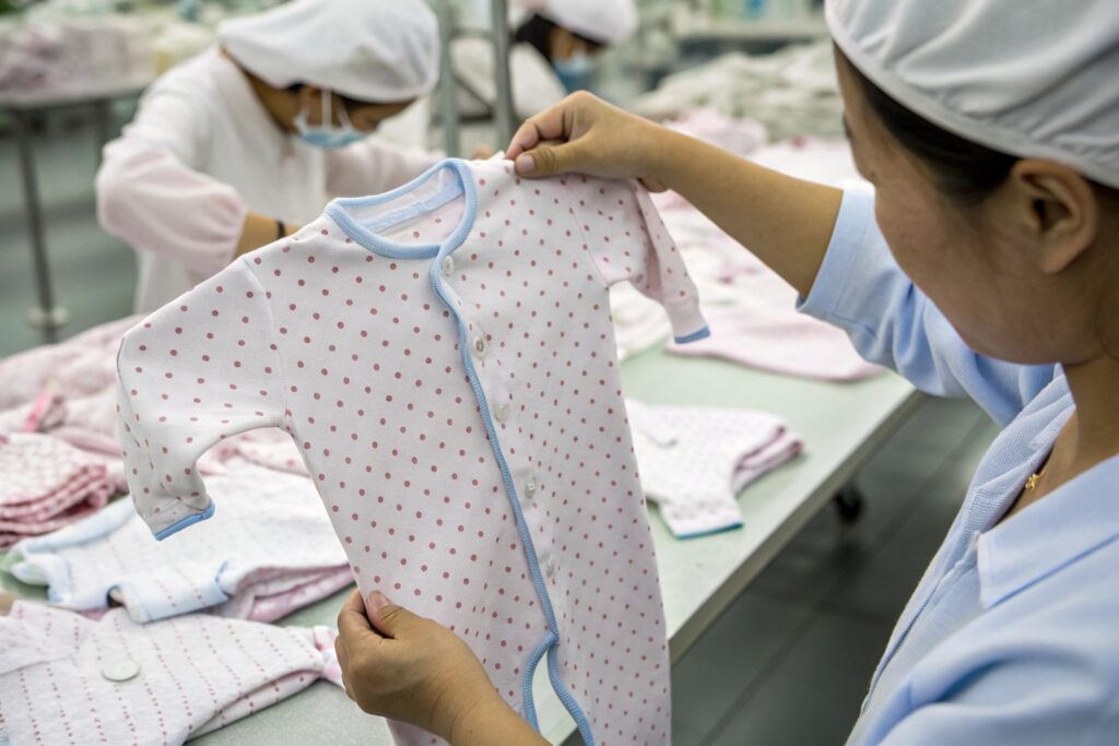 Close-up view of newborn babywear garment being inspected in the factory