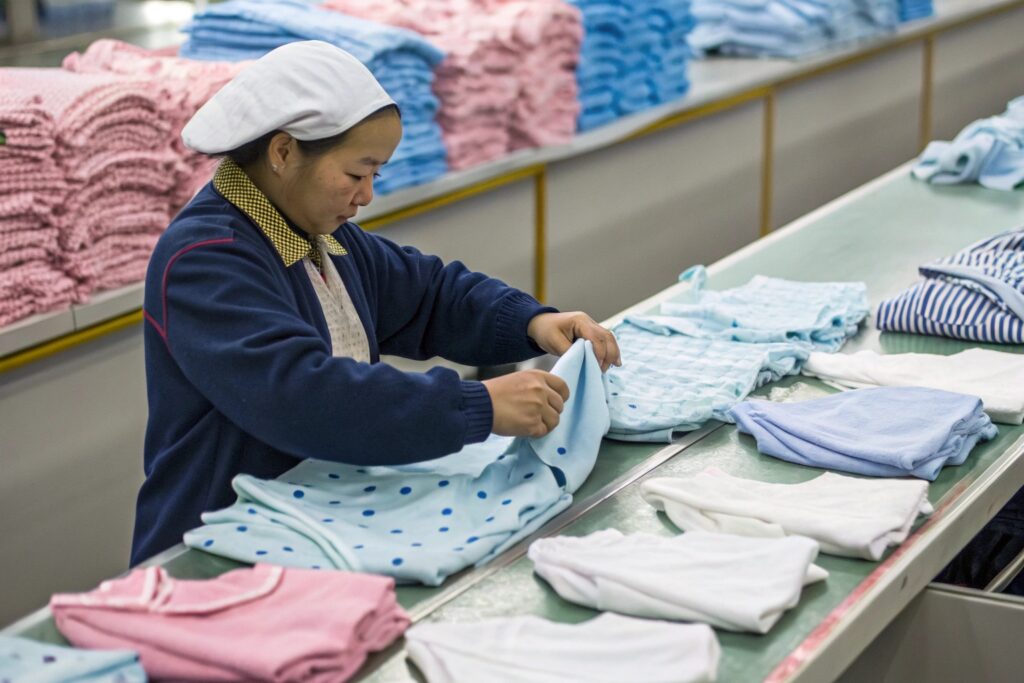 Factory worker organizing babywear items Factory worker organizing babywear items