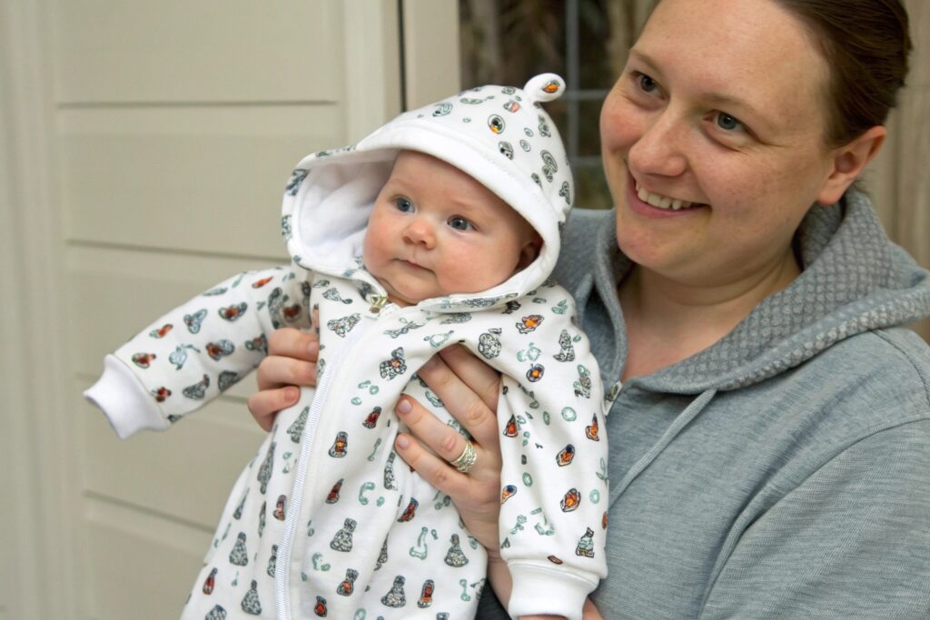 Parent holding their baby in a cute hooded outfit