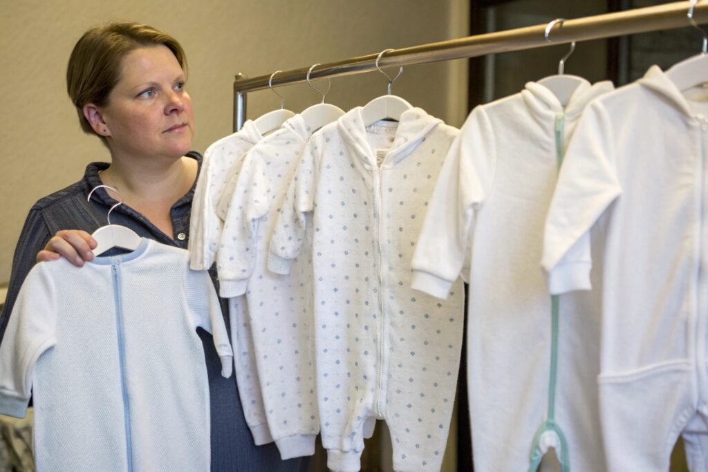 European Parent Standing in Front of a Rack of Babywear