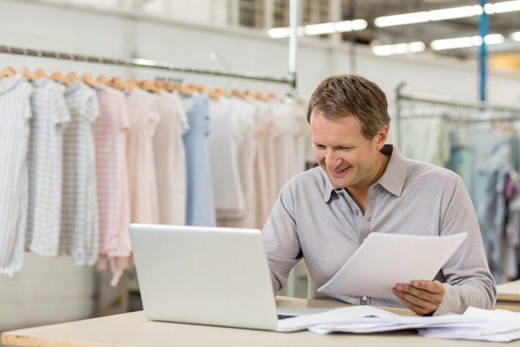 Business owner receiving report while reviewing babywear production