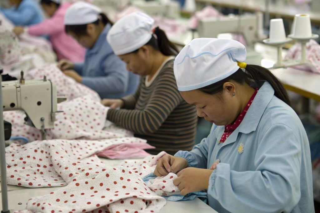 Workers stitching children's clothing in factory