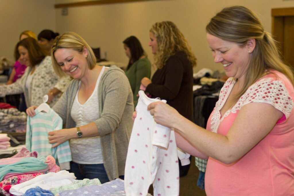 Group of moms sorting baby clothes