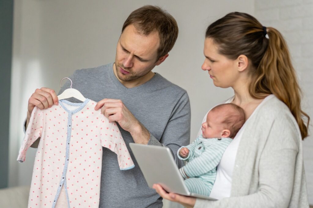 Parents comparing baby clothes while looking at a laptop