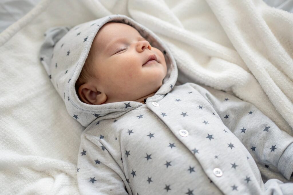Baby sleeping in a soft grey star-patterned onesie with a hood