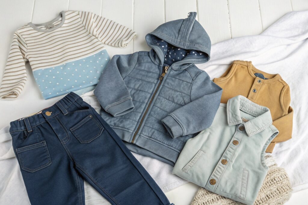 A set of kids' clothing, including striped sweater, hoodie, and vest, with denim pants and a cute mustard-colored shirt