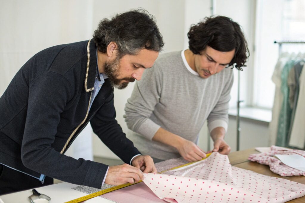 Two professionals measuring and preparing fabric for garment creation
