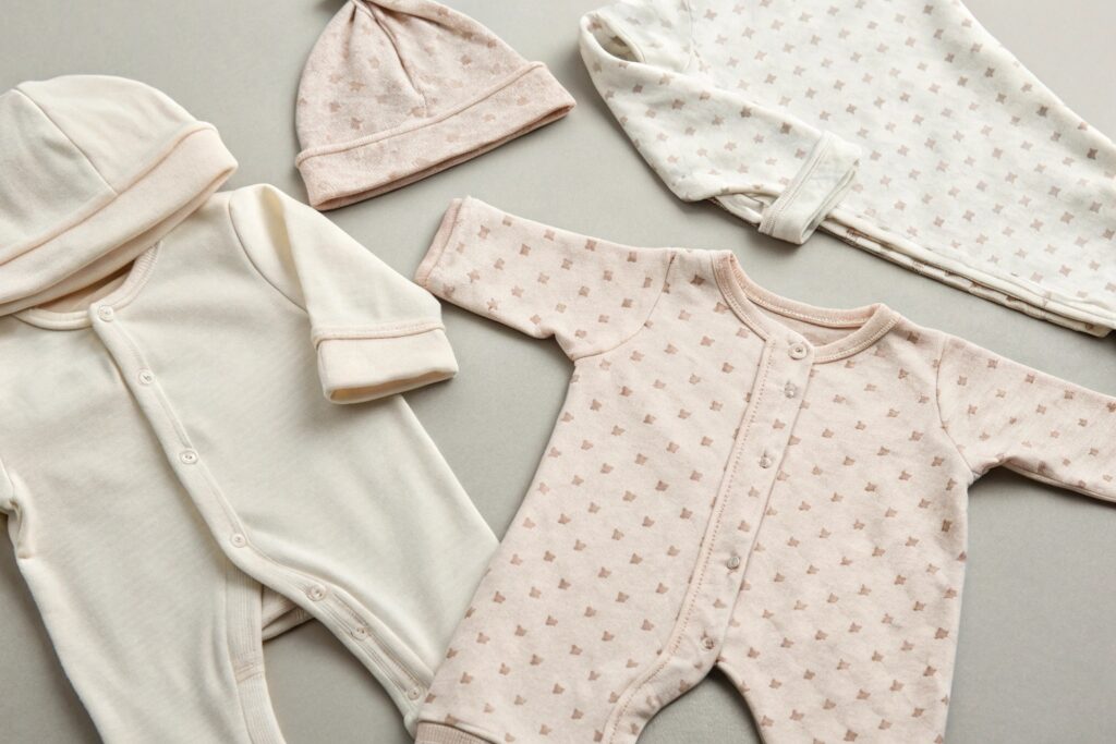 Soft cotton baby onesies and hats in pastel pink and beige, perfect for newborns